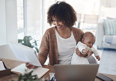 Buy stock photo Shot of a young woman using a laptop while caring for her adorable baby girl at home