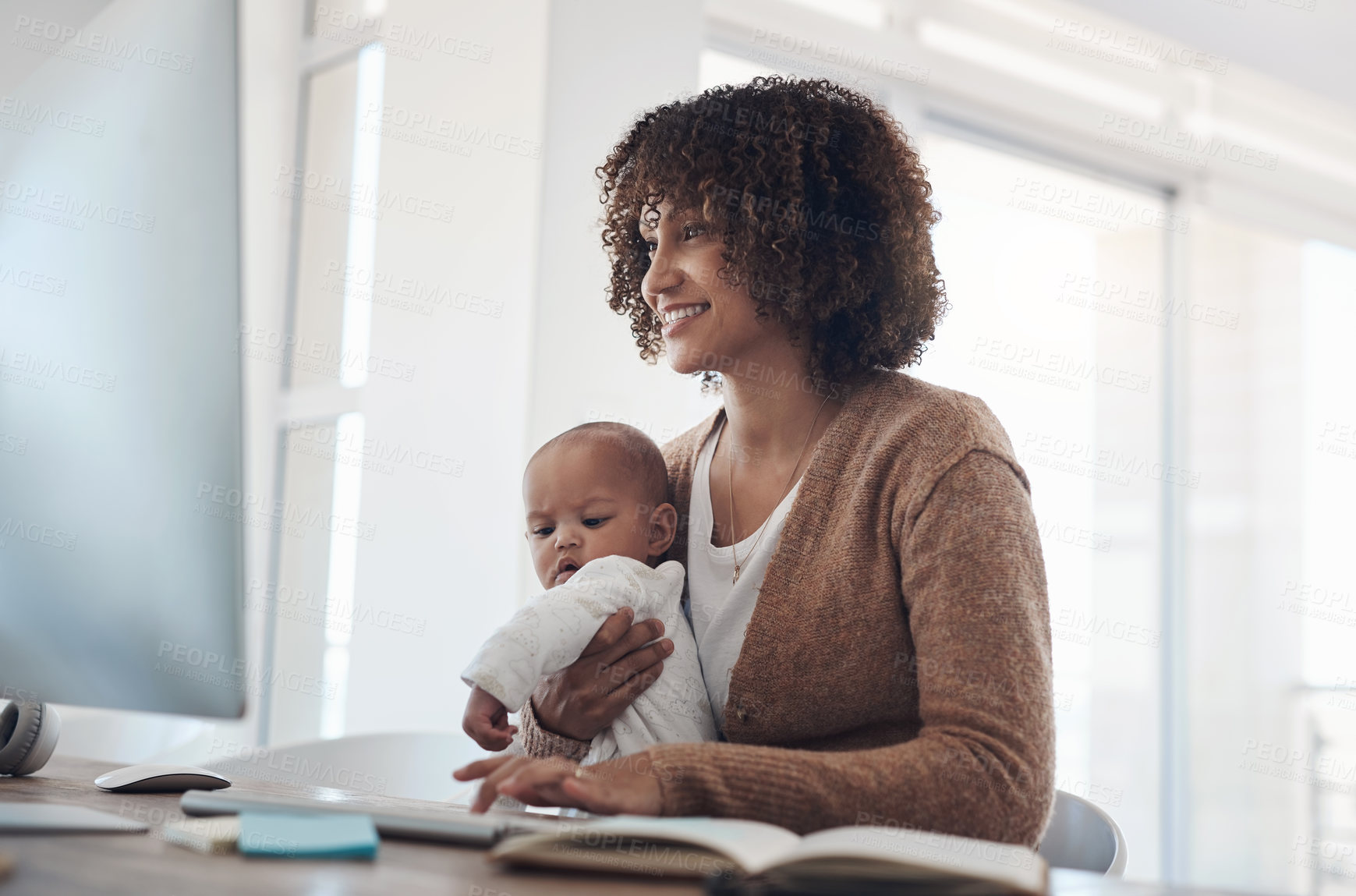 Buy stock photo Shot of a young woman using a computer while caring for her adorable baby girl at home