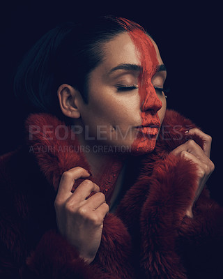 Buy stock photo Studio shot of a young woman posing with paint on her face on a black background