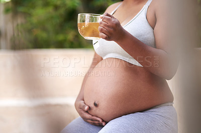 Buy stock photo Cropped shot of a pregnant woman drinking tea while wearing exercise clothes