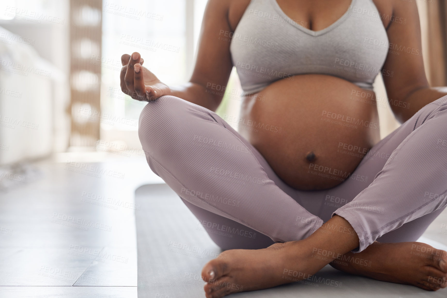 Buy stock photo Cropped shot of a pregnant woman doing yoga at home