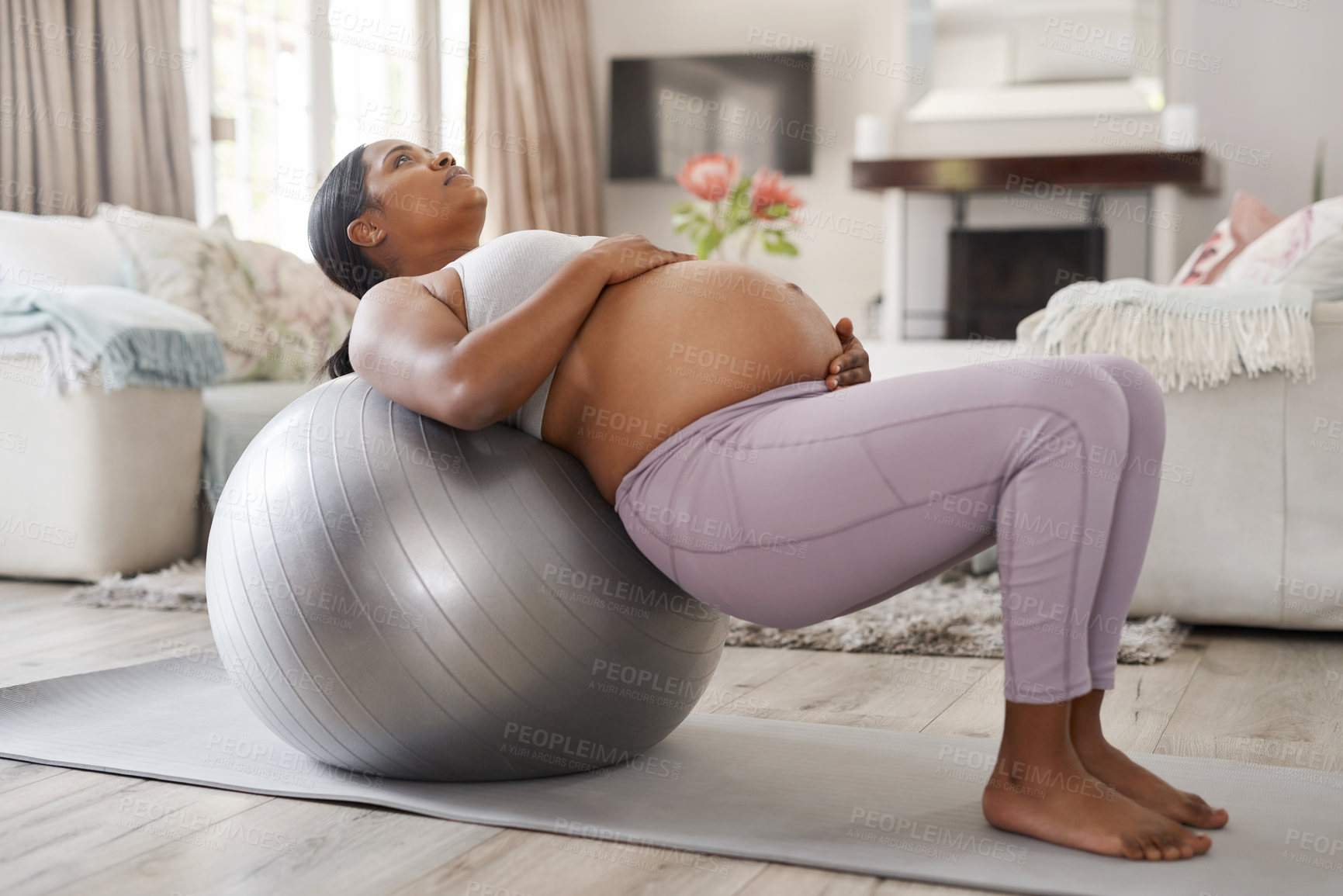 Buy stock photo Shot of a beautiful young pregnant woman exercising at home