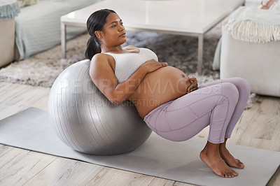 Buy stock photo Shot of a beautiful young pregnant woman exercising at home