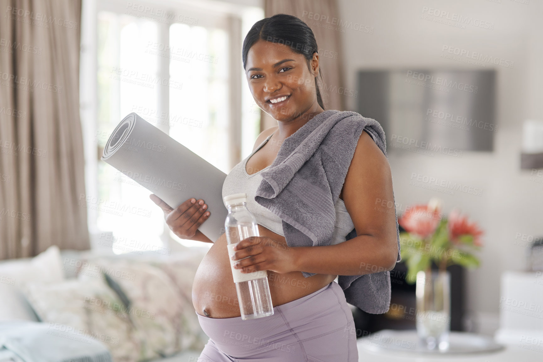 Buy stock photo Shot of a pregnant woman holding a water bottle and yoga mat at home