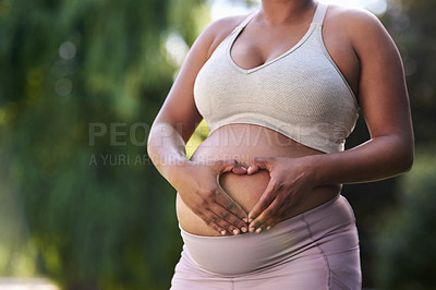 Buy stock photo Shot of a woman forming a heart shape on her pregnant belly