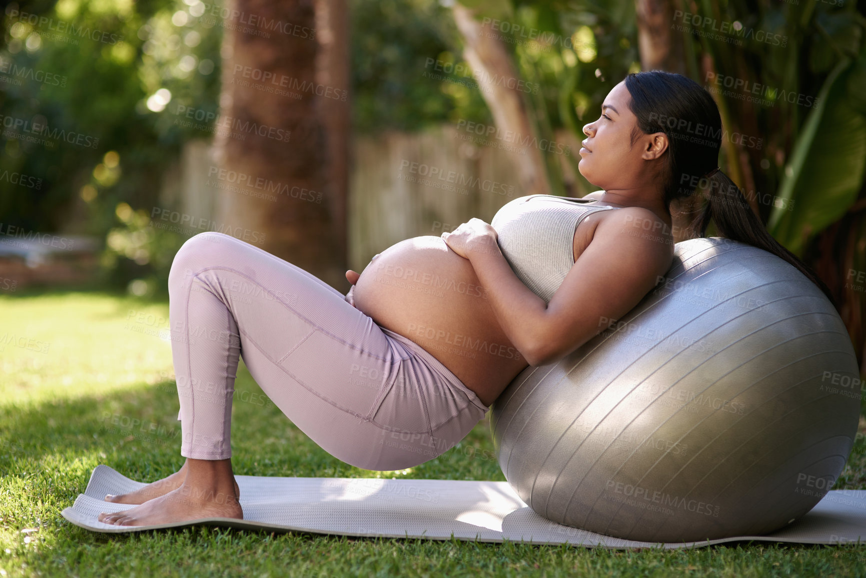 Buy stock photo Shot of a pregnant woman working out with a stability ball outside