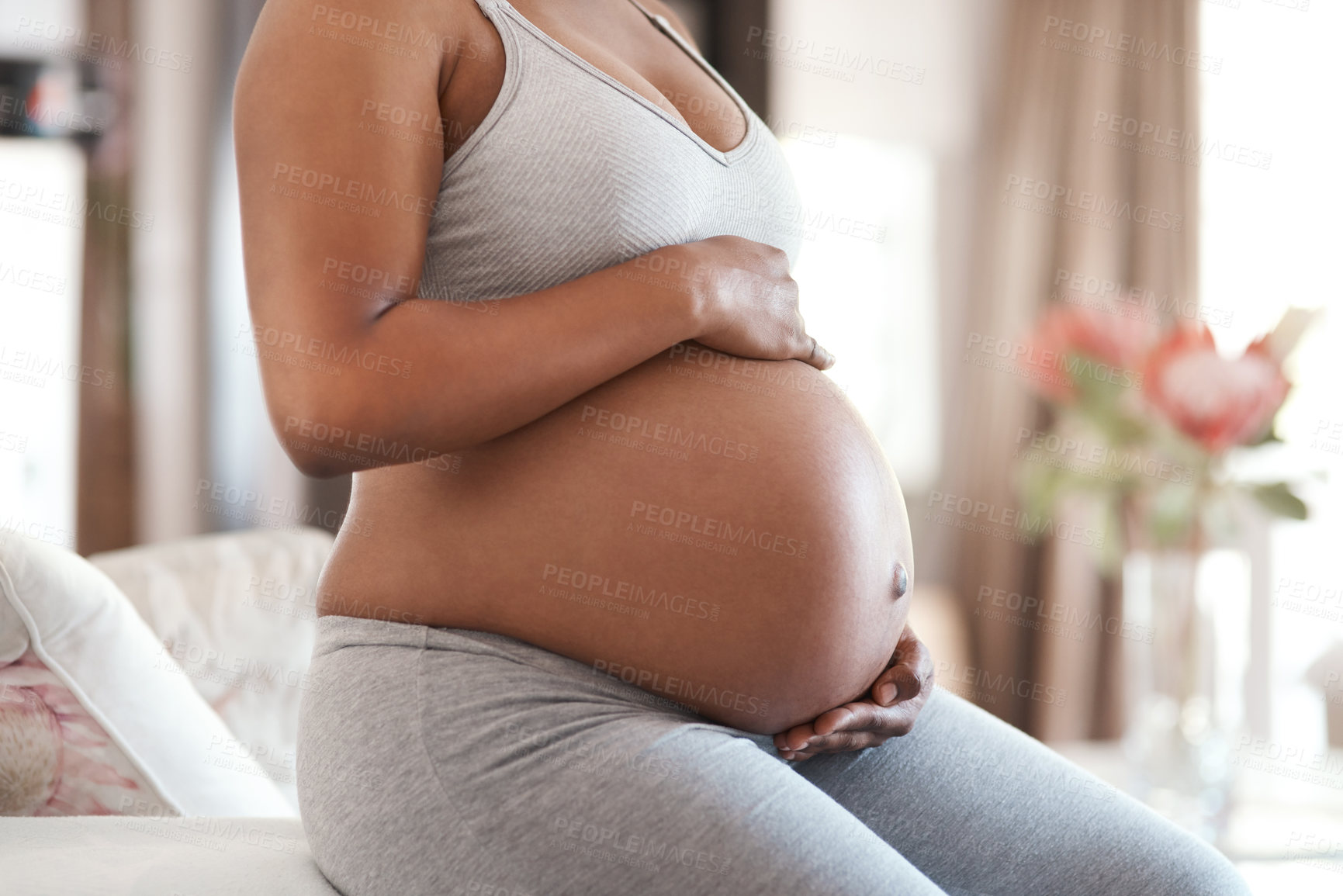 Buy stock photo Closeup shot of an unrecognisable woman touching her pregnant belly at home