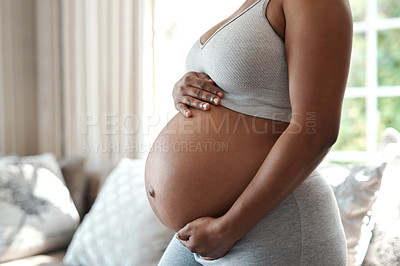 Buy stock photo Closeup shot of an unrecognisable woman touching her pregnant belly at home