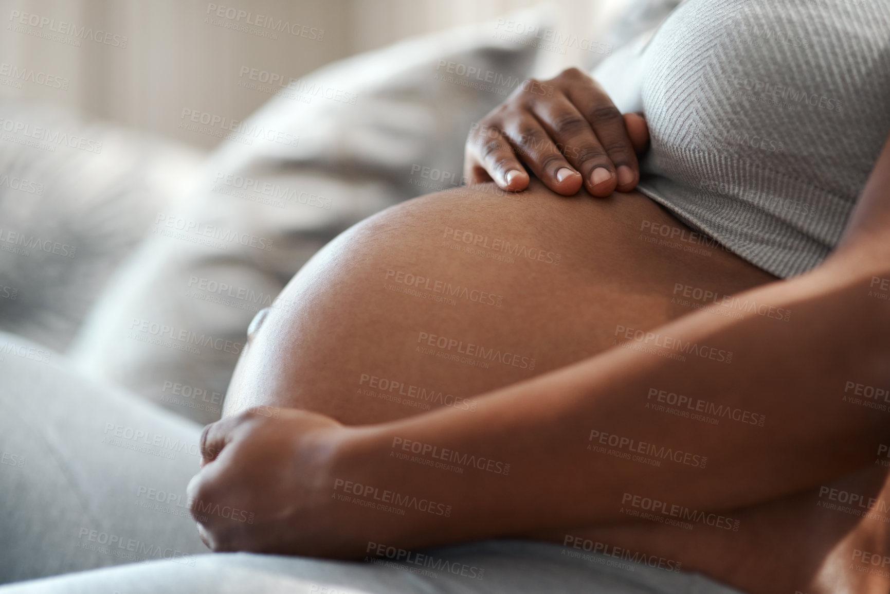 Buy stock photo Closeup shot of an unrecognisable woman touching her pregnant belly at home