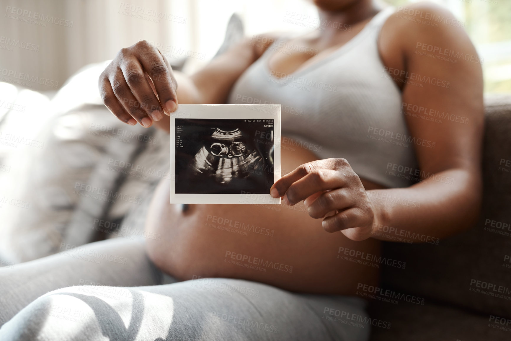 Buy stock photo Closeup shot of an unrecognisable woman holding a sonogram at home