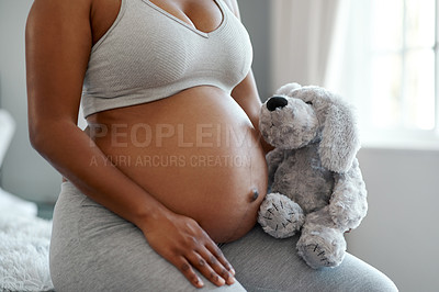 Buy stock photo Closeup shot of an unrecognisable woman holding a stuffed teddybear close to her pregnant belly at home
