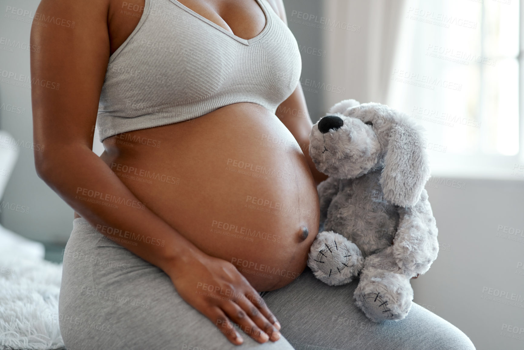 Buy stock photo Closeup shot of an unrecognisable woman holding a stuffed teddybear close to her pregnant belly at home