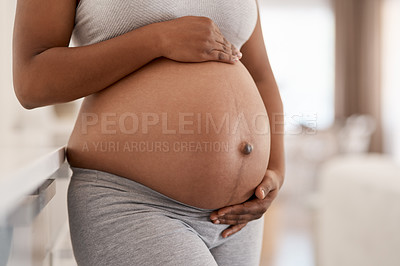 Buy stock photo Closeup shot of an unrecognisable woman touching her pregnant belly at home