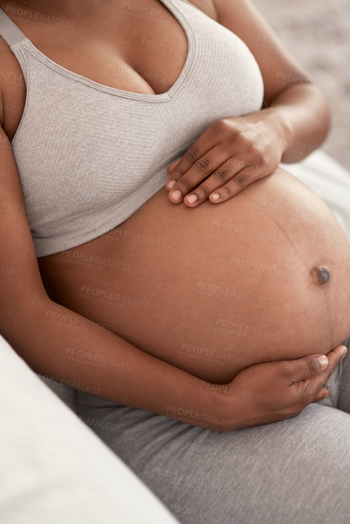 Buy stock photo Closeup shot of an unrecognisable woman touching her pregnant belly at home