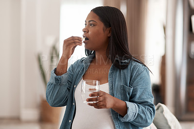 Buy stock photo Shot of a pregnant woman taking medication at home