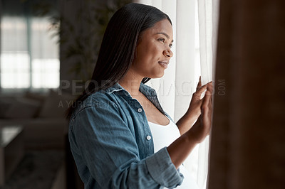 Buy stock photo Shot of a pregnant woman looking out the window at home