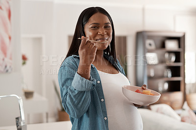 Buy stock photo Portrait of a pregnant woman eating a bowl of fruit at home