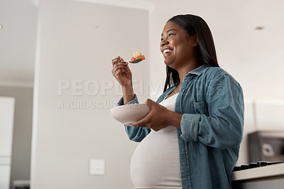 Buy stock photo Low angle shot of a pregnant woman eating a bowl of fruit at home