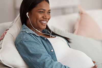 Buy stock photo Shot of a pregnant woman listening to music while relaxing at home