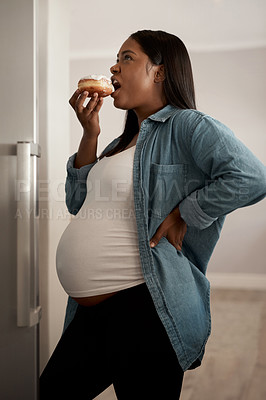 Buy stock photo Shot of a pregnant woman eating a donut at home