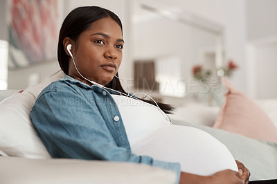 Buy stock photo Shot of a pregnant woman listening to music while relaxing at home