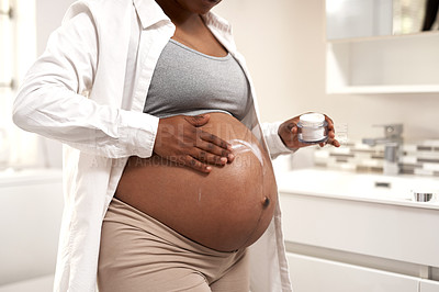 Buy stock photo Closeup shot of a pregnant woman applying cream on her stomach at home