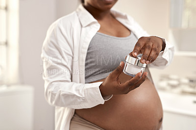 Buy stock photo Closeup shot of a pregnant woman holding a jar of cream for her stomach at home