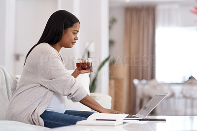 Buy stock photo Shot of a pregnant woman drinking tea and using her laptop while sitting at home