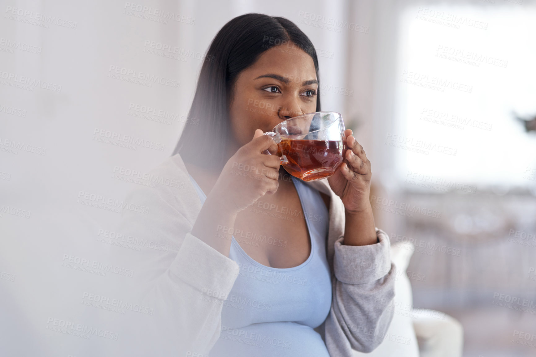 Buy stock photo Shot of a pregnant woman drinking tea and while sitting at home