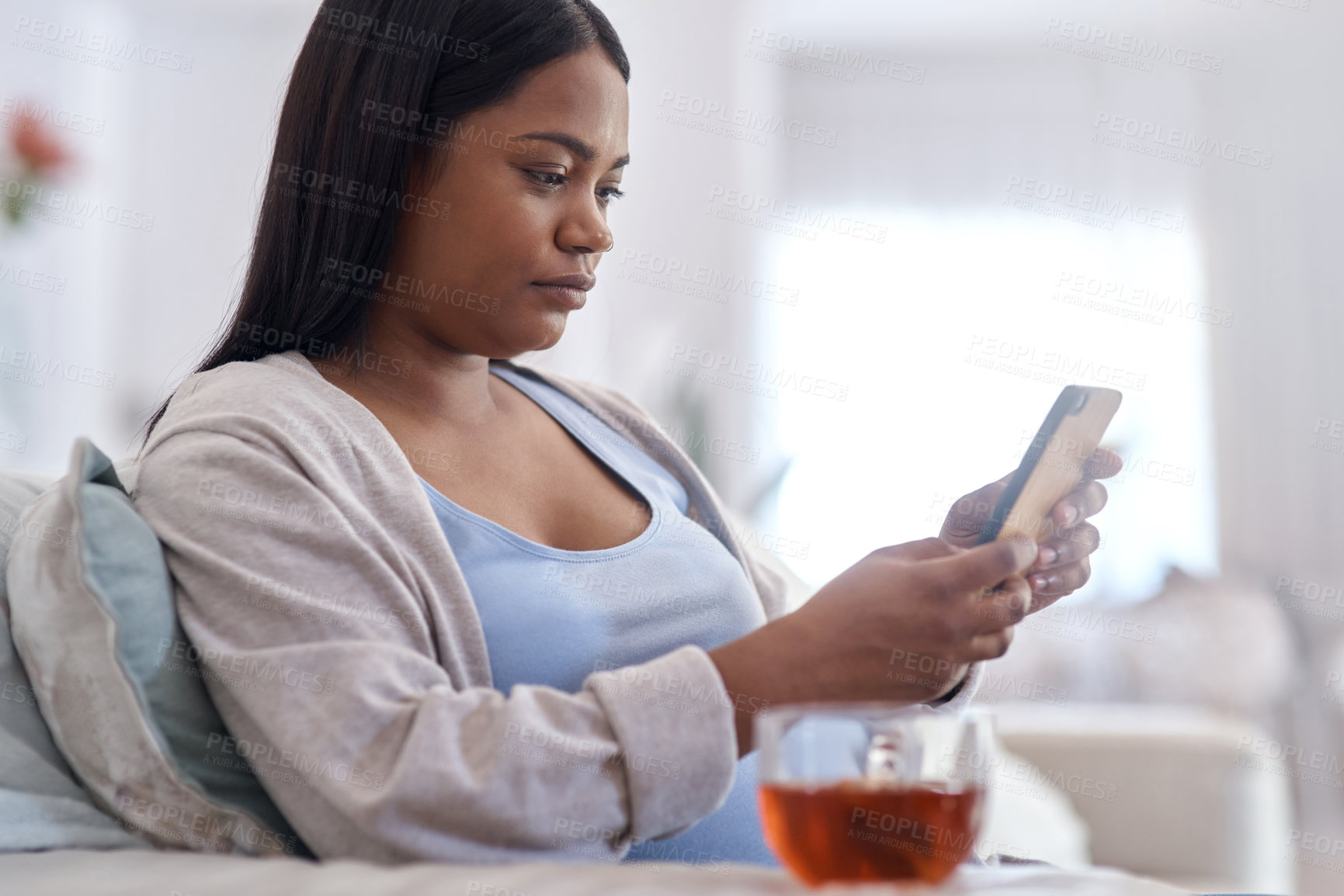 Buy stock photo Shot of a woman using her cellphone while sitting at home