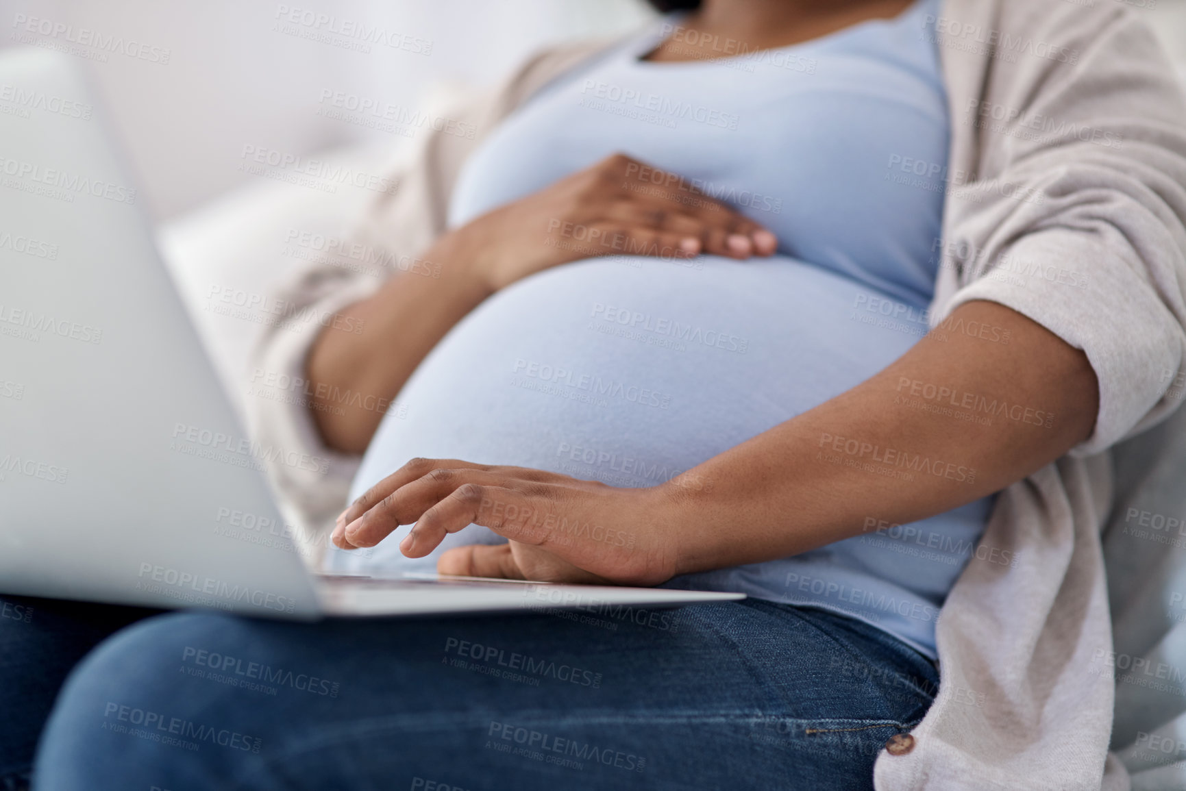 Buy stock photo Cropped shot of a pregnant woman using her laptop while sitting at home