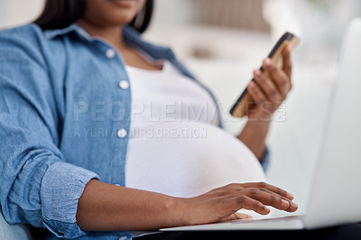 Buy stock photo Cropped shot of a pregnant woman holding her cellphone while working on her laptop