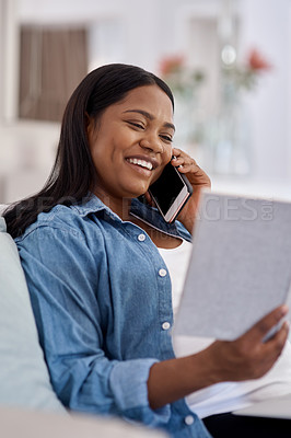 Buy stock photo Shot of a woman looking at her notebook while talking on her cellphone at home