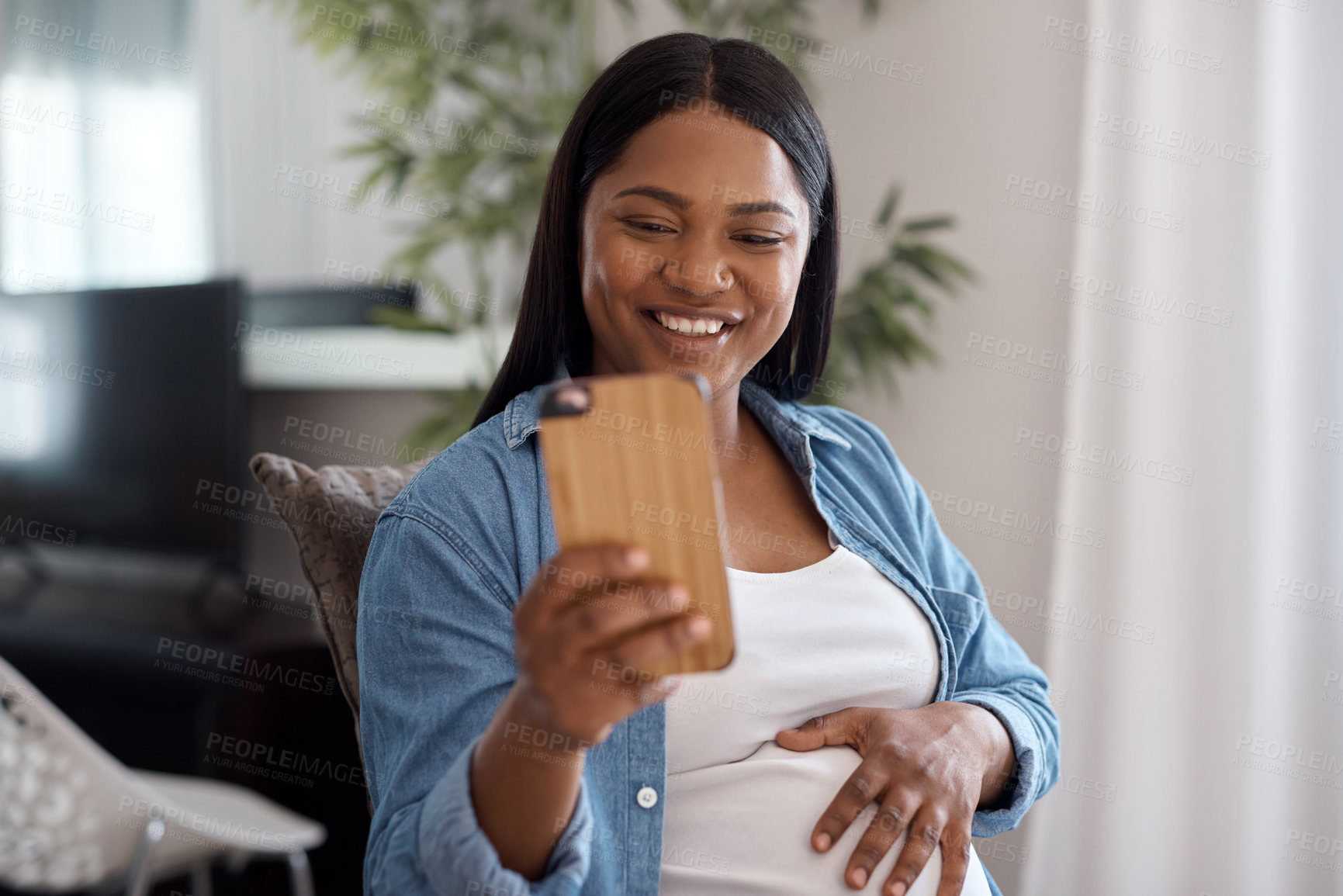 Buy stock photo Shot of a pregnant woman taking a selfie while sitting on the sofa at home