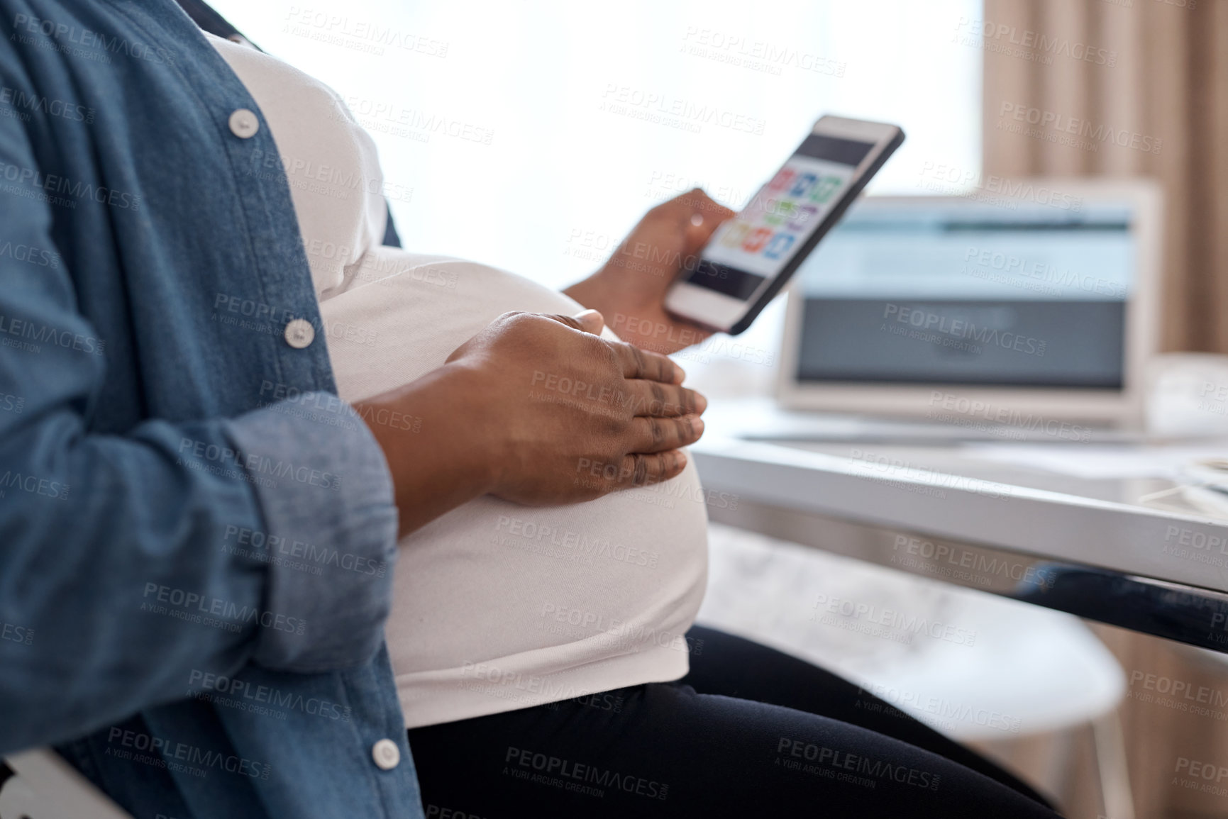 Buy stock photo Cropped shot of a pregnant woman using her cellphone while sitting at home
