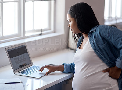 Buy stock photo Shot of a pregnant woman using her laptop while sitting at home