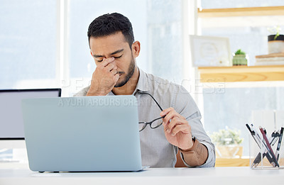 Buy stock photo Shot of a young man having a headache at work in a modern office