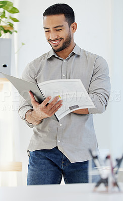 Buy stock photo Shot of a young man reading a document at work in a modern office