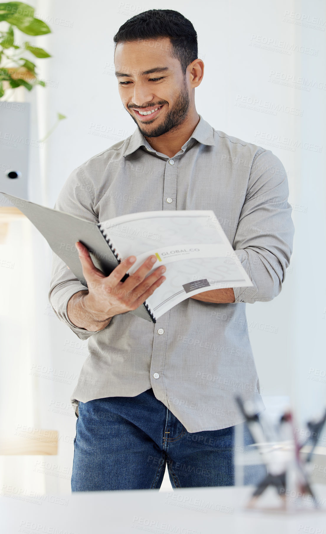 Buy stock photo Shot of a young man reading a document at work in a modern office
