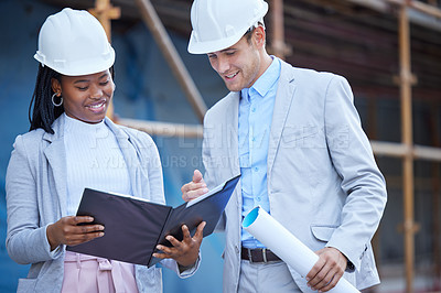 Buy stock photo Shot of two coworkers looking over plans at a construction site