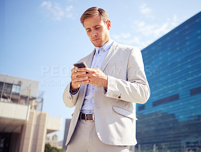 Buy stock photo Serious, phone and business man in city for reading email, news or typing on website outdoor in low angle. Mobile,  professional or consultant in street for social media, network or scroll online app