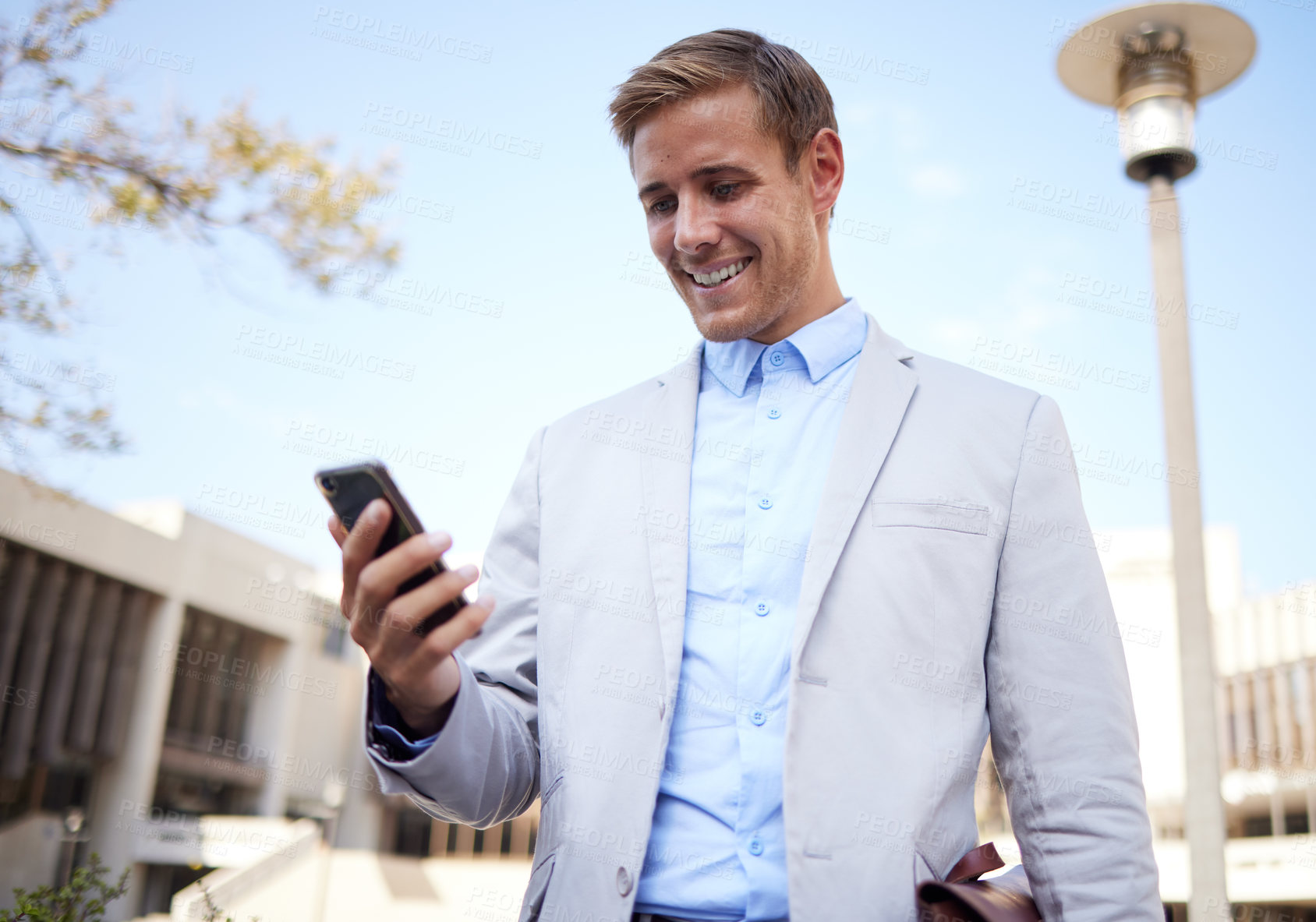 Buy stock photo Shot of a young businessman using a cellphone in the city