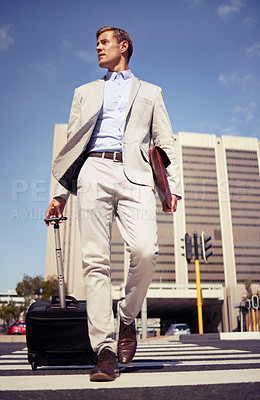 Buy stock photo Shot of a young businessman walking with a suitcase in the city