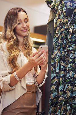 Buy stock photo Shot of a young woman using her smartphone while shopping