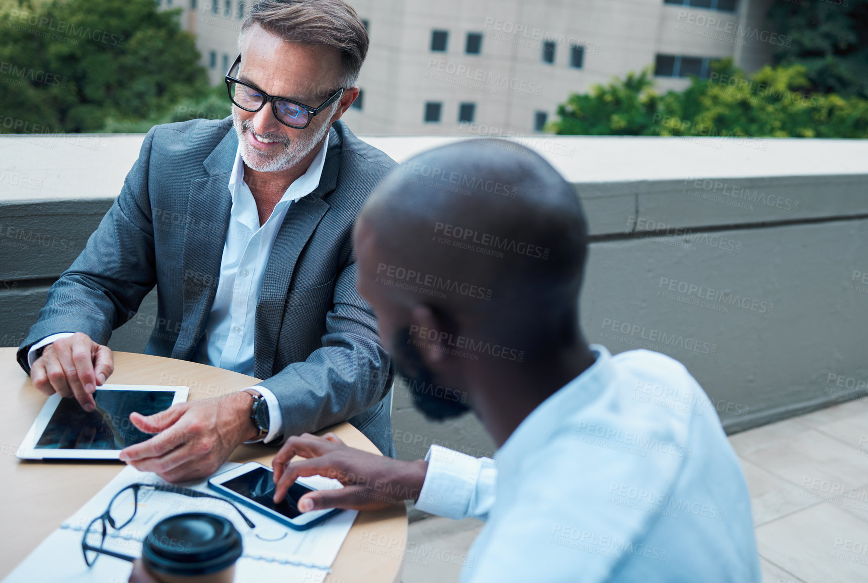 Buy stock photo Mature businessman, tablet and meeting outdoors with partner, colleague and planning on balcony. Team, appointment and corporate men at table with technology for brainstorm, discussion and ideas