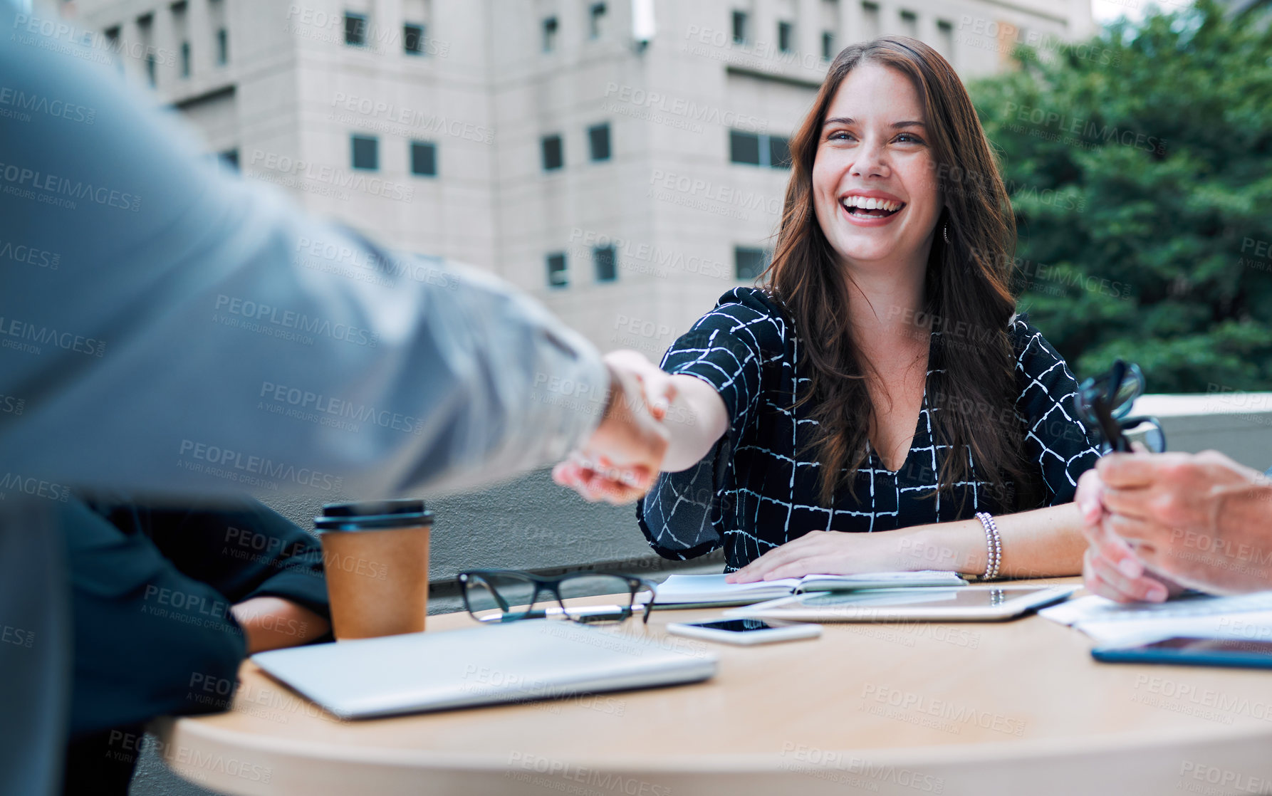 Buy stock photo Shot of a young businesswoman shaking hands with a colleague during a meeting on the balcony of an office