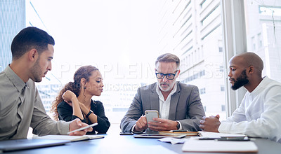 Buy stock photo Shot of a group of businesspeople using a smartphone during a meeting in a modern office