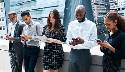 Buy stock photo Shot of businesspeople using various devices against an urban background