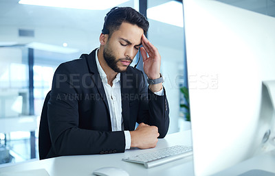 Buy stock photo Shot of a young businessman experiencing a headache at his desk