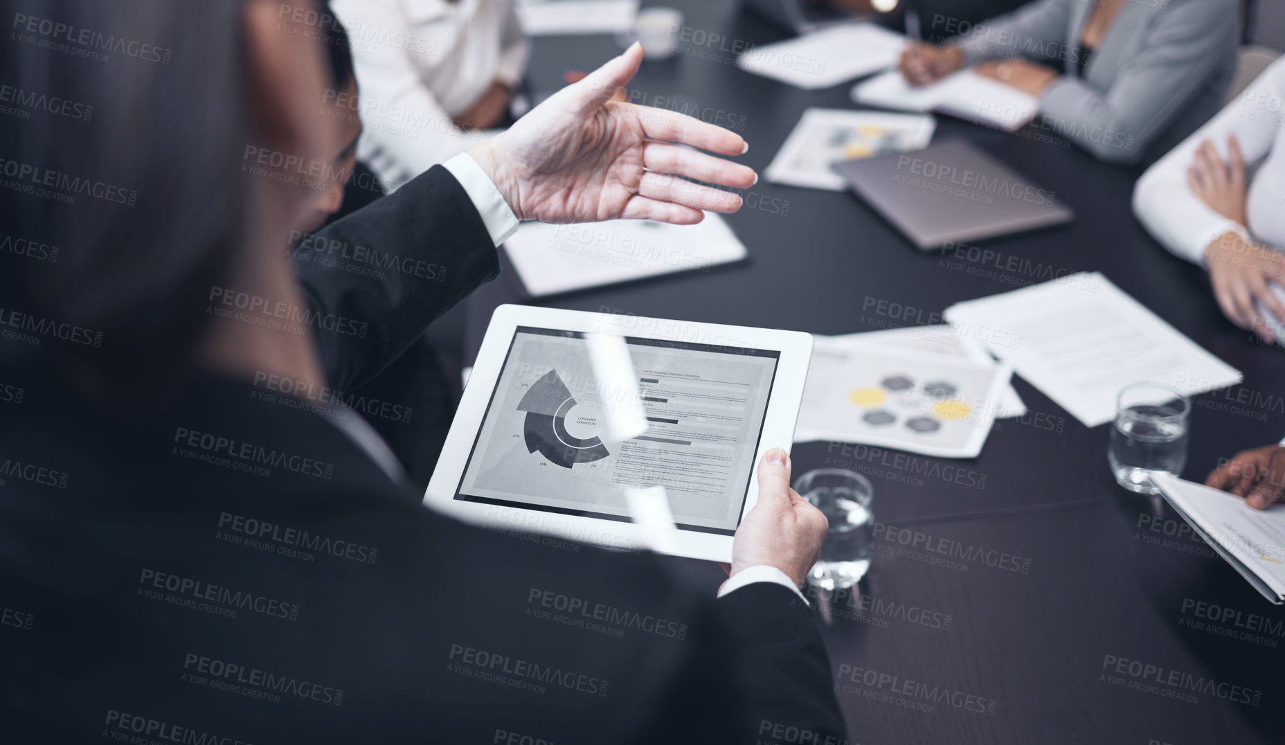 Buy stock photo Shot of a mature businesswoman using a digital tablet during a business meeting